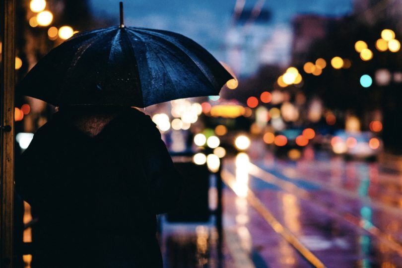 Standing in the rain under an umbrella